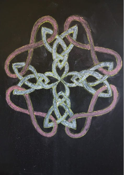 Dibujo de formas en tiza sobre pizarrón: entrelazado en blanco y rosa de simetría cuádruple